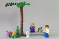 Minifigure of boy giving a bouquet of flowers to his girlfriend in a forest garden on