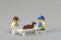 Florianopolis, Brazil. September 19, 2020: Vet minifigure giving injection to a dog while its owner distracts him with a bone on