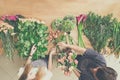 Florist and assistant in flower shop delivery make rose bouquet, table top view