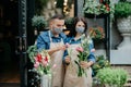 Florist collects bouquet of different flowers. Millennial designers man and woman decorate composition