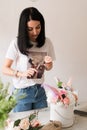 the florist collects a bouquet of flowers smiling brunette girl in a white t-shirt with flowers