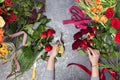 Florist creates a bouquet in a flower shop. Top view of creating a bouquet of red, orange, burgundy, yellow roses Royalty Free Stock Photo