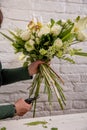 The florist creates a floral arrangement of roses, lilacs, callas, carnations, hydrangeas, brasica, alstroemeria, ornithogalum,