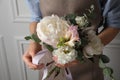 Florist creating beautiful bouquet at white wall, closeup Royalty Free Stock Photo