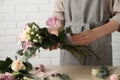 Florist creating beautiful bouquet at wooden table indoors, closeup Royalty Free Stock Photo
