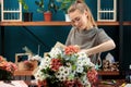 Florist makes a bouquet of multi-colored chrysanthemums. A young adult girl works with enthusiasm