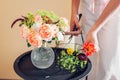 Florist makes bouquet of roses zinnia amaranth flowers in vase on table. Process of arranging with basket and pruner Royalty Free Stock Photo