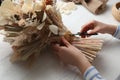 Florist making beautiful bouquet of dried flowers at white table, closeup Royalty Free Stock Photo