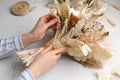 Florist making beautiful bouquet of dried flowers at white table, closeup Royalty Free Stock Photo