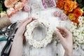 Florist making wicker wreath decorated with tiny daisies