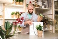 Florist putting beautiful potted plant into paper bag