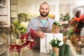 Florist putting beautiful potted plant into paper bag