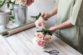 Florist`s workplace: flowers and accessories on a light wooden table. Stylish floristry. Royalty Free Stock Photo