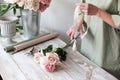 Florist`s workplace: flowers and accessories on a light wooden table. Stylish floristry. The woman collects a bouquet of fresh flo Royalty Free Stock Photo