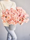 The florist takes care of the flowers. A woman holds an aluminum vase with peach-colored bush spray roses in her hands