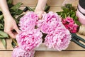 Florist at work: woman making floral decoration of pink peonies