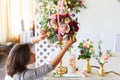 Florist at work. Woman making spring floral decorations the wedding table , the bride and groom. Flowers, candles, a bottle of ch