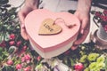 Florist workplace: flowers, accessories, tools. Female hands holding a gift box in the shape of a heart Royalty Free Stock Photo