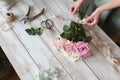 Partial view of the florist making a bouquet of flowers in a light workshop on a wooden surface. Royalty Free Stock Photo