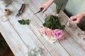 Partial view of the florist making a bouquet of flowers in a light workshop on a wooden surface. Royalty Free Stock Photo