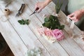 Partial view of the florist making a bouquet of flowers in a light workshop on a wooden surface. Royalty Free Stock Photo