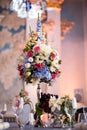 Floristic decoration of the festive table, a large vase with bright flowers, a festive dinner in honor of the wedding, table