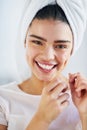 Floss as much as you brush. Portrait of a beautiful young woman flossing her teeth in the bathroom at home. Royalty Free Stock Photo