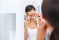 Flossing away. Shot of a cheerful attractive young woman flossing her teeth while looking at her reflexion in a mirror Royalty Free Stock Photo