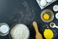 Flour, baking powder, cinnamon, eggs, lemon and rolling pin for rolling dough on a black background