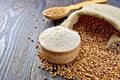 Flour buckwheat in bowl and spoon with cereals on board