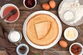 Flour, eggs, honey, sugar and a Stack of fried pancakes on a brown background.