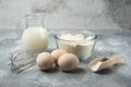 Flour, eggs, milk and whisker on marble background