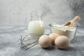 Flour, eggs, milk and whisker on marble table