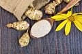 Flour of Jerusalem artichoke in spoon with vegetable on dark boa