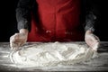 Flour on a kitchen table with a black moody background in the morning light. Female hands sifting flour, making dough.