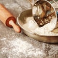 Flour metal bowl with wooden rolling pin on stone table Royalty Free Stock Photo