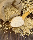 Flour oat in spoon with grains on board