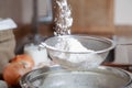 White flour is poured into a sieve over a bowl Royalty Free Stock Photo