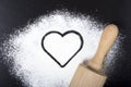 Flour and rolling pin with a heart symbol. Flour on a black back Royalty Free Stock Photo