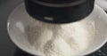 Flour sifting with mug sieve close up