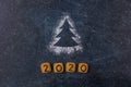 Flour Silhouette Christmas Tree with cookies digits 2020 on dark background with copy space. delicious bakery sweet confectionery