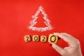 Flour Silhouette Christmas Tree with cookies digits 2020 on red background with women hand