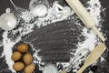 flour sprinkled with different kitchen tools on dark black background. Baking ingredient Top view.