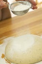 Flour is sprinkled over a ball of dough on a wooden board Royalty Free Stock Photo