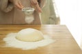 Flour is sprinkled over a ball of dough on a wooden board Royalty Free Stock Photo