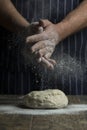 Flour is sprinkled over a ball of dough on wooden board by hand Royalty Free Stock Photo