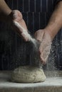 Flour is sprinkled over a ball of dough on wooden board by hand Royalty Free Stock Photo