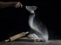 Flour is sprinkled over a ball of dough on a wooden board with r