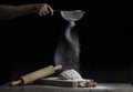 Flour is sprinkled over a ball of dough on a wooden board with r Royalty Free Stock Photo