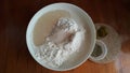 Flour,tremors, salt, sugar, water in a white bowl on a wooden table. Cooking process. Pancakes recipe.